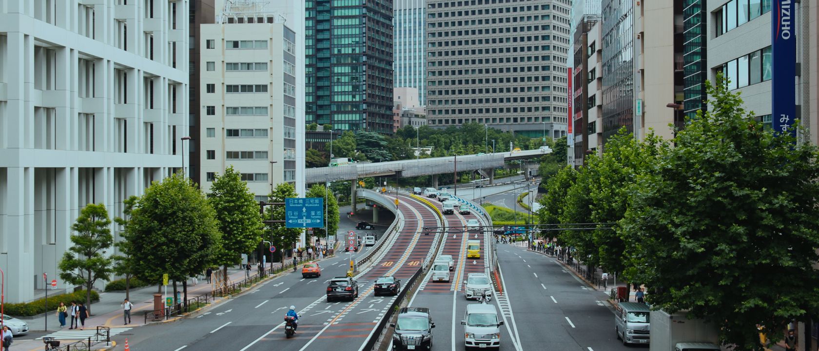 Urban view of a bustling street in Tokyo with modern skyscrapers and heavy traffic.
