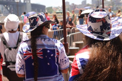 Free People in Australian attire celebrating at Sydney Harbour under bright sunlight. Stock Photo
