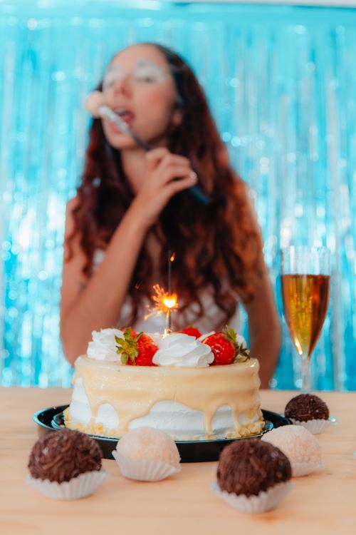 Free Woman enjoying cake with a sparkler and champagne on a festive occasion. Stock Photo