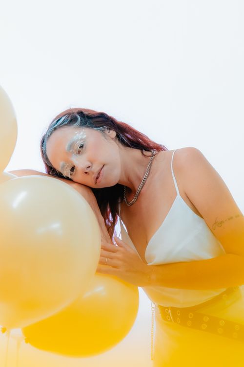 Free A serene portrait of a woman surrounded by golden balloons. Stock Photo