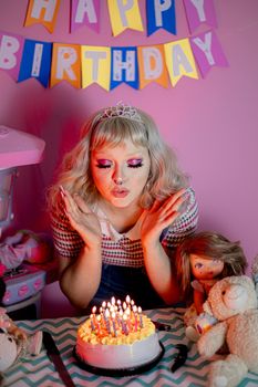 Woman blowing out candles on birthday cake with party decorations and toys.
