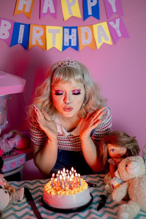 Free Woman blowing out candles on birthday cake with party decorations and toys. Stock Photo