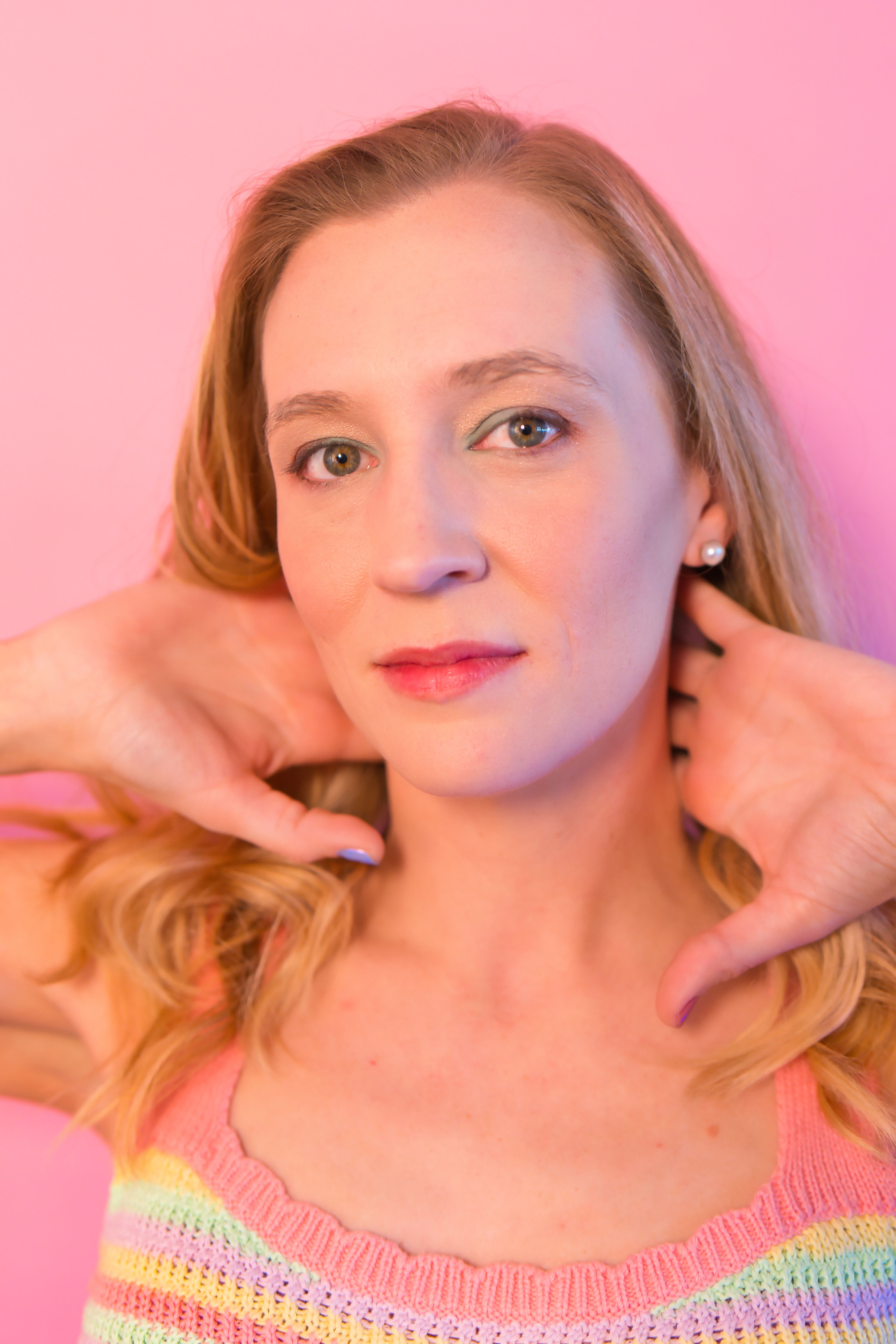 Vibrant portrait of a woman against a pink background, highlighting her confident expression.