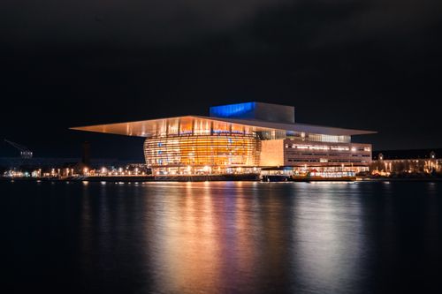 Free Stunning night view of the illuminated Copenhagen Opera House reflecting in the water. Stock Photo