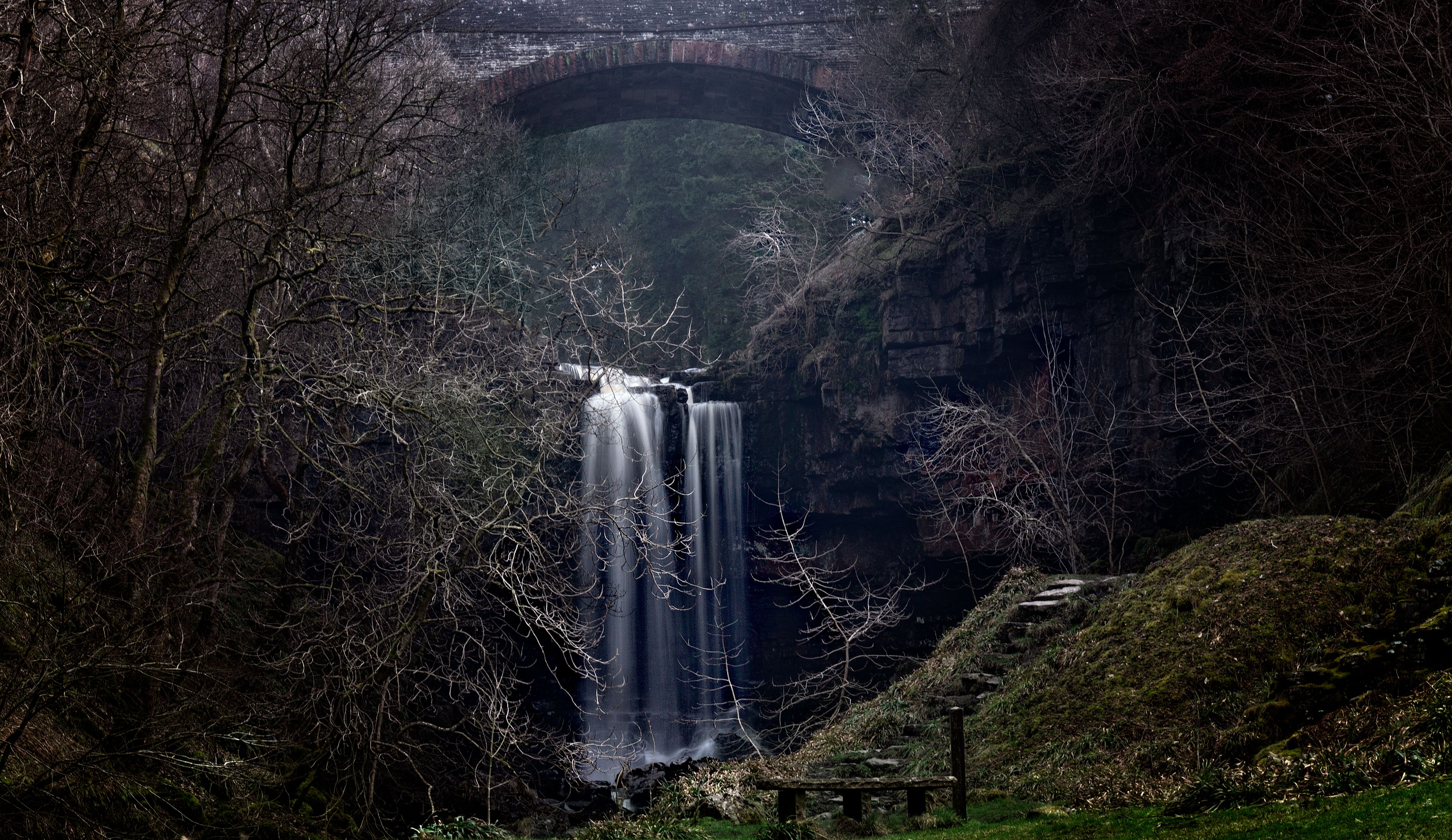 Serene waterfall under rustic stone bridge · Free Stock Photo