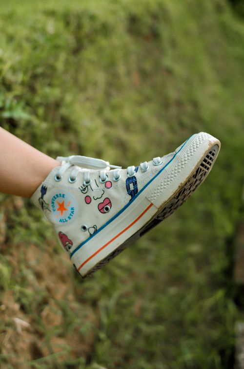 Free Vibrant blue high top sneaker with cartoon prints in an outdoor setting. Stock Photo