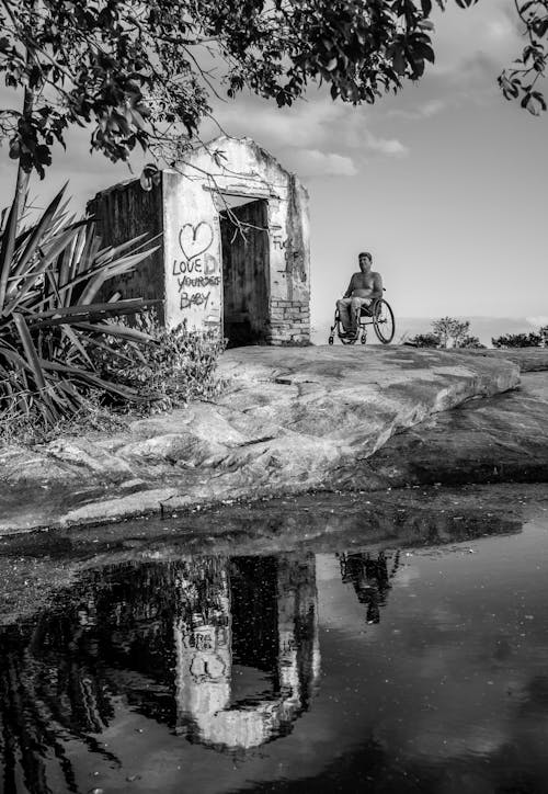 Grayscale Photography of Person Sitting on Wheelchair Near Pond