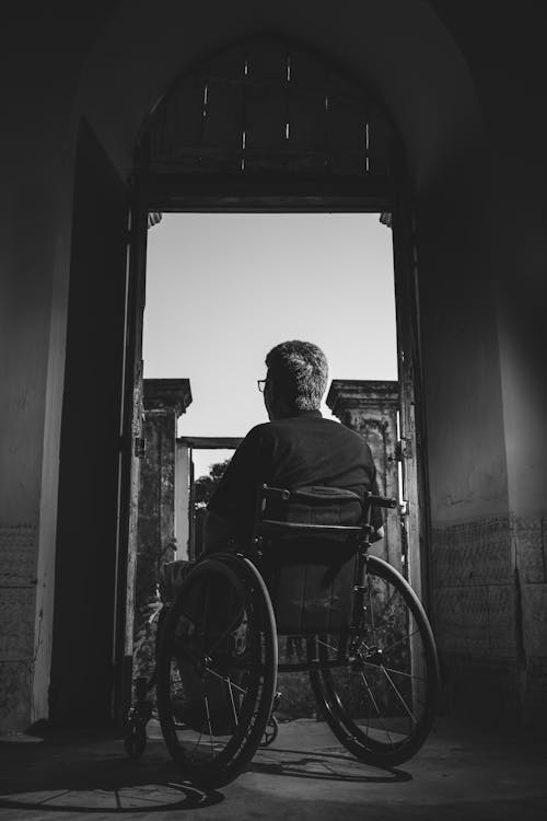 бесплатная Фотография человека, сидящего в инвалидной коляске в оттенках серого Стоковое фото