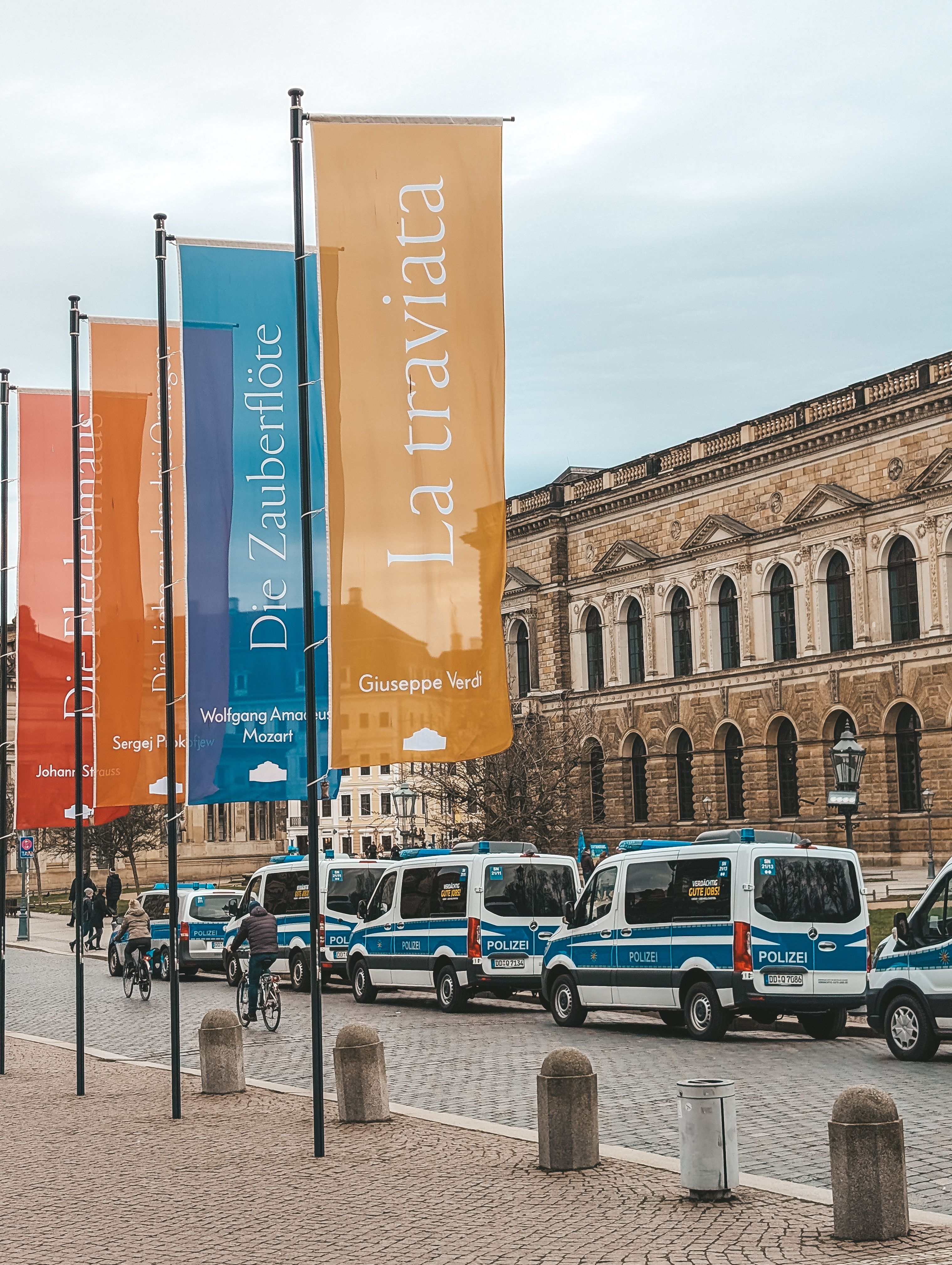 Street scene featuring vibrant flags, police vans, and historic architecture in a European city.
