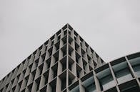 在多云的天空下，现代建筑呈现低角度视图，带有几何网格图案