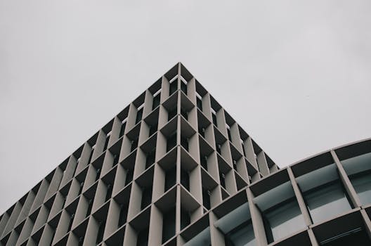 在多云的天空下，现代建筑呈现低角度视图，带有几何网格图案