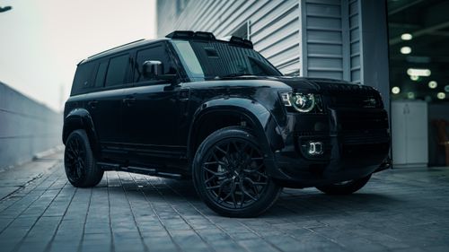 Free A modern black SUV with tinted windows parked outside an urban building. Stock Photo