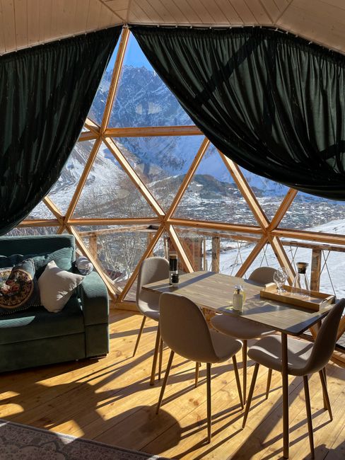 Geodesic dome interior with a stunning mountain view, cozy seating and dining area.