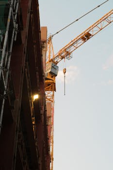 A towering construction crane beside a building in Bratislava at dusk.