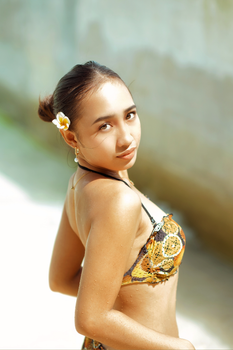 Young woman in patterned swimwear, looking back, flower in hair.
