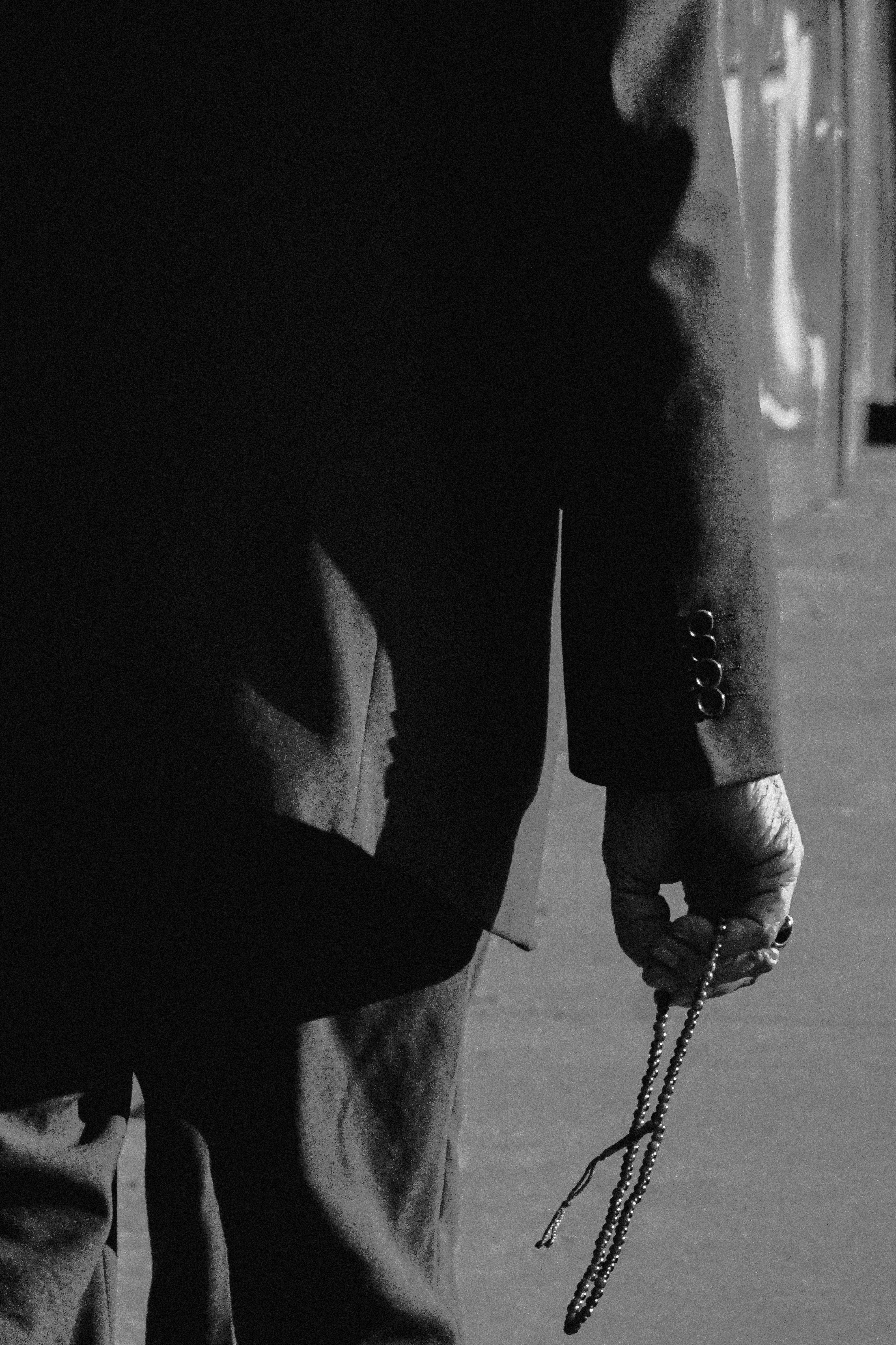 Gratuit Prim-plan monocrom al mâinii unei persoane care ține mărgele de rugăciune, evocând contemplația și pacea. Fotografie de stoc