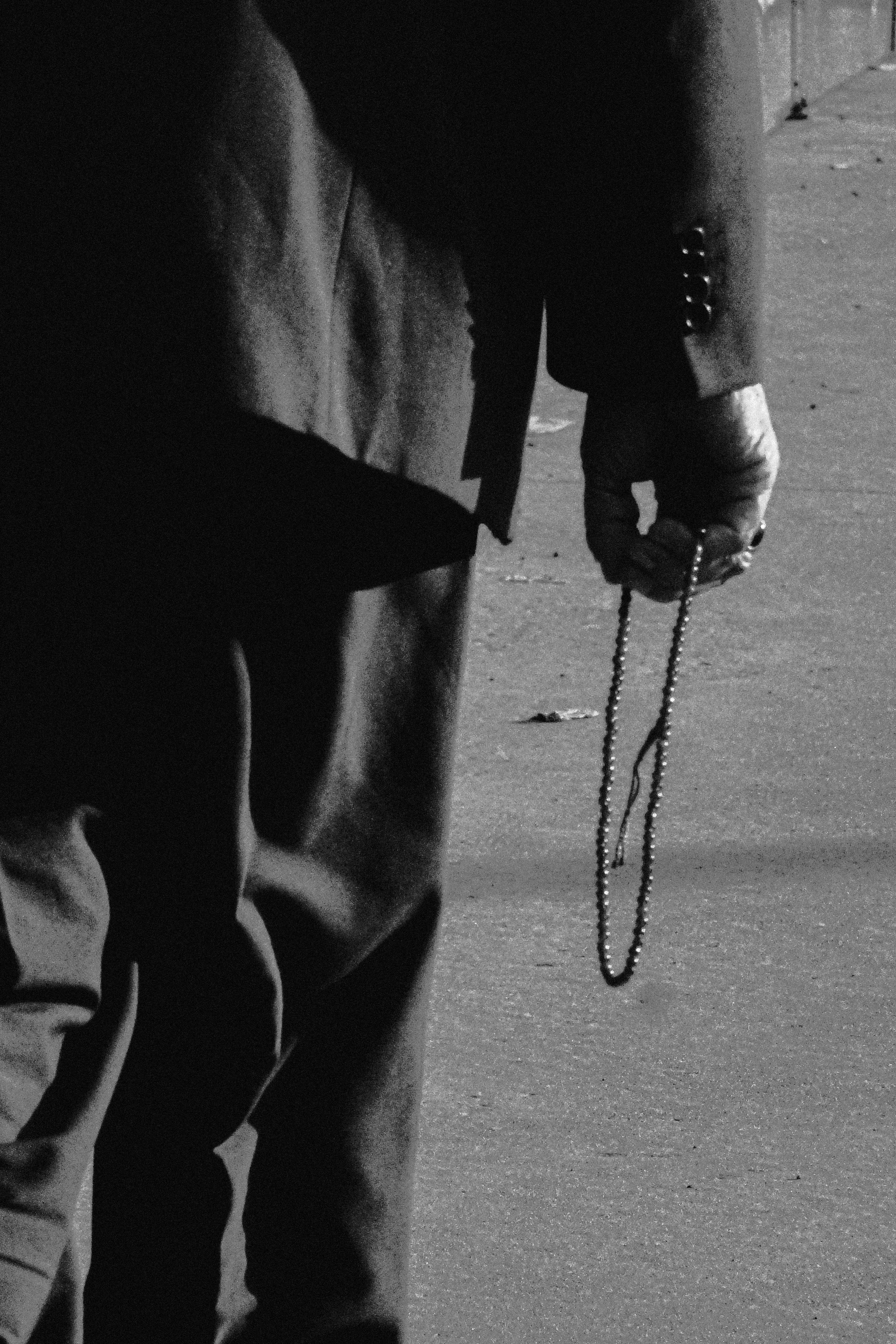 Gratuit Une photo monochrome d'une personne en costume tenant un chapelet, créant une ambiance contemplative. Photos