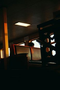 A solitary passenger on a vintage bus during sunset, invoking nostalgia and solitude.