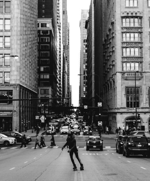 Free A skater rolling through a busy Chicago street, framed by towering architecture. Stock Photo