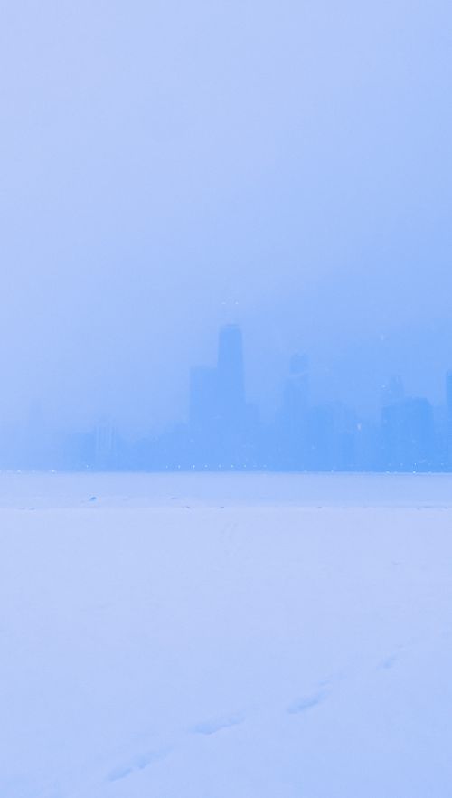 Free A serene view of the Chicago skyline shrouded in mist and snow, creating a tranquil winter scene. Stock Photo