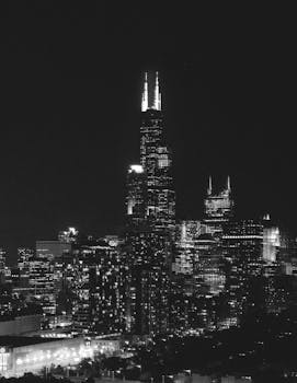 Monochrome photo capturing the iconic Chicago skyline featuring the Willis Tower at night.