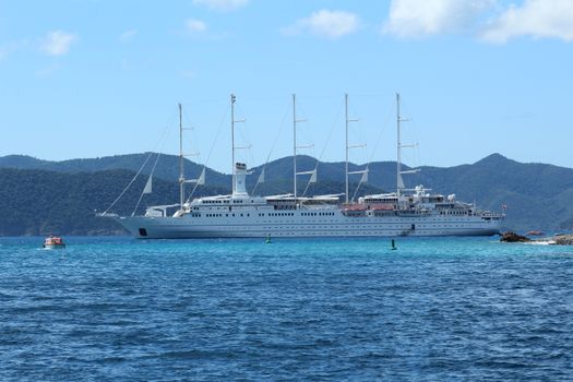 A majestic luxury cruise ship sailing in clear blue tropical waters.