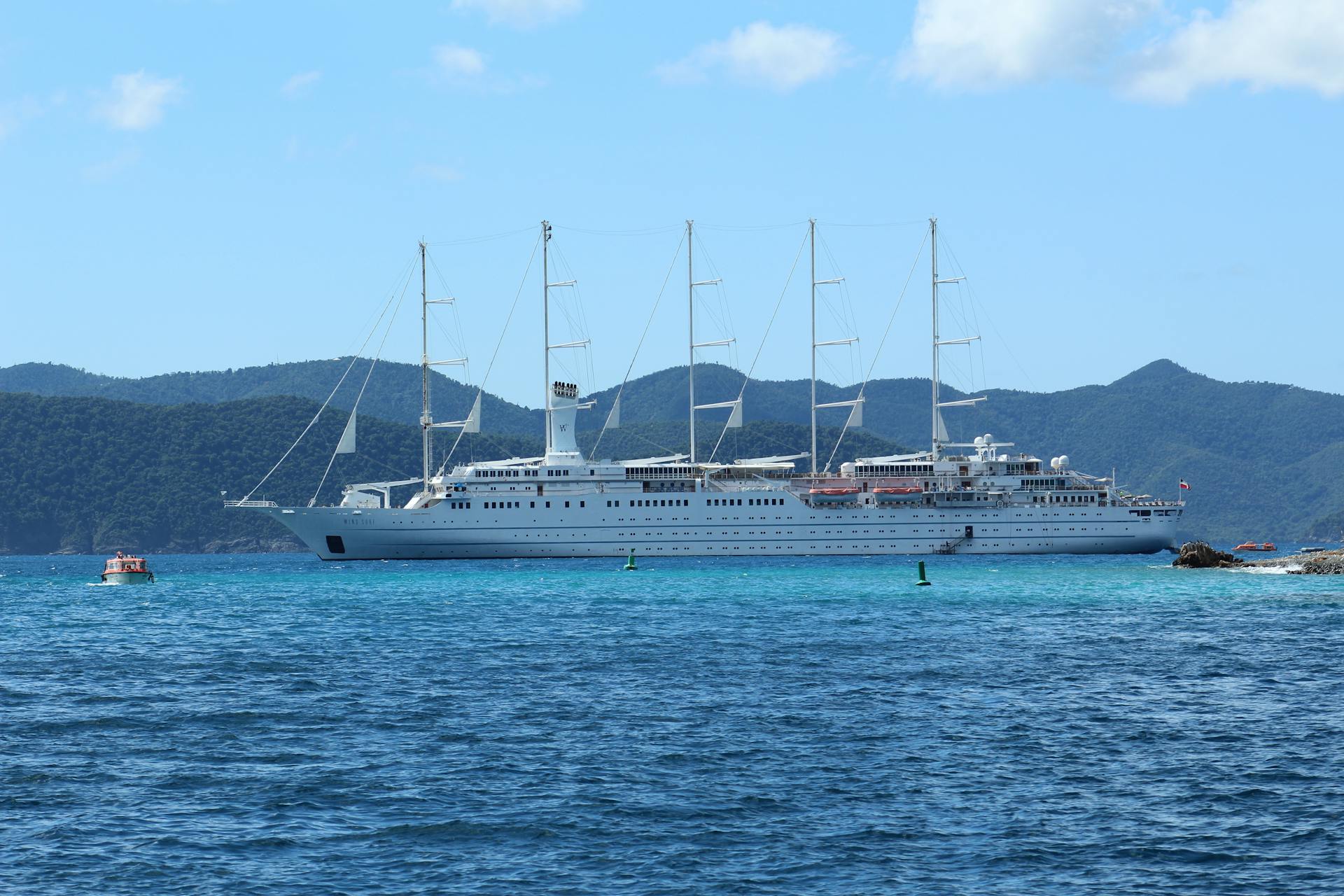 A majestic luxury cruise ship sailing in clear blue tropical waters.