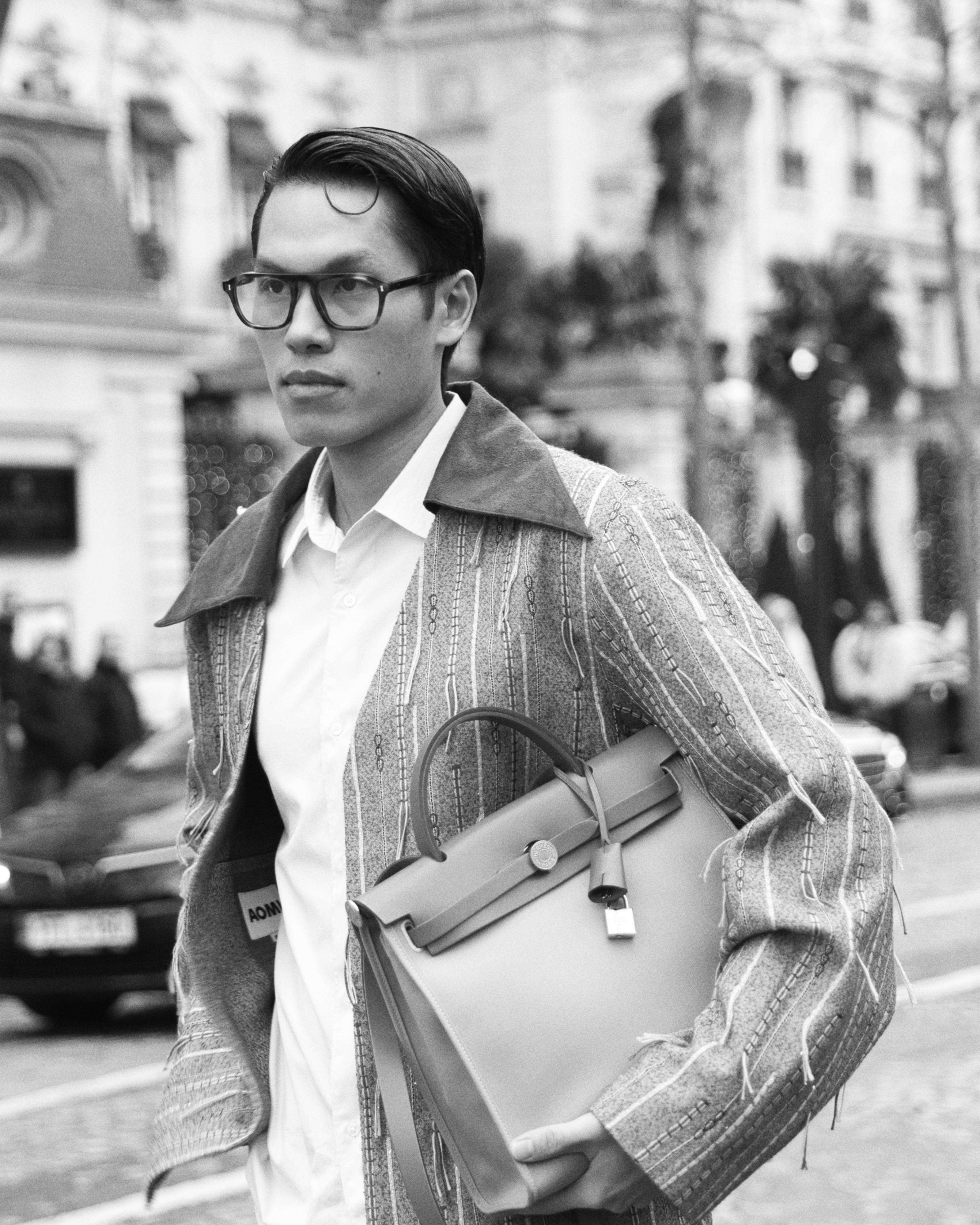 Free Stylish adult wearing designer coat and bag in Paris setting. Classic street fashion moment. Stock Photo