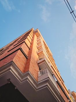 Low-angle view of a brick building with balconies in Bucaramanga, Colombia against a bright sky.