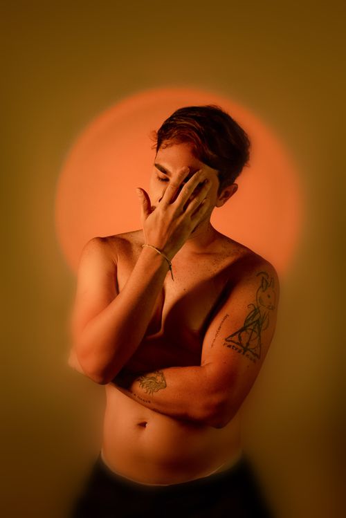 Free A moody artistic portrait of a man with tattoos and dramatic lighting. Stock Photo