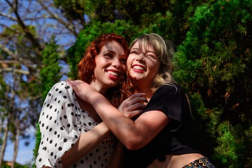 Free Two women embracing and smiling in a sunlit park, capturing a moment of joy and friendship. Stock Photo
