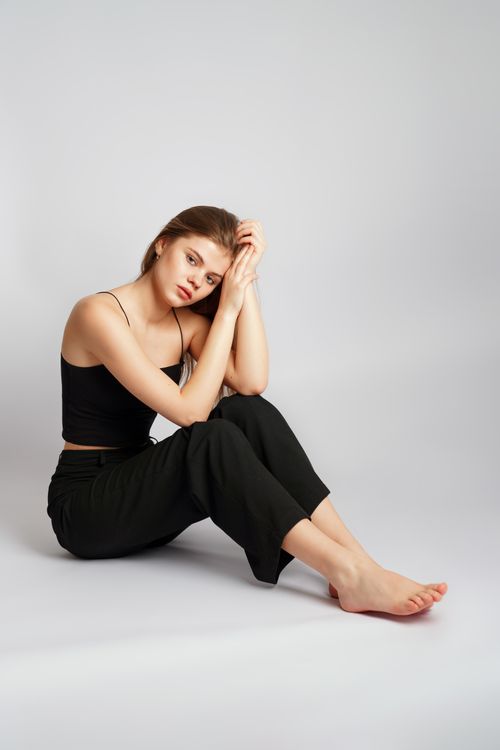 Free Elegant portrait of a woman seated in a minimalist studio setting, showcasing contemplative expression. Stock Photo