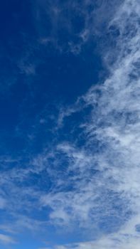 Vivid blue sky with wispy white clouds creating a dramatic contrast.