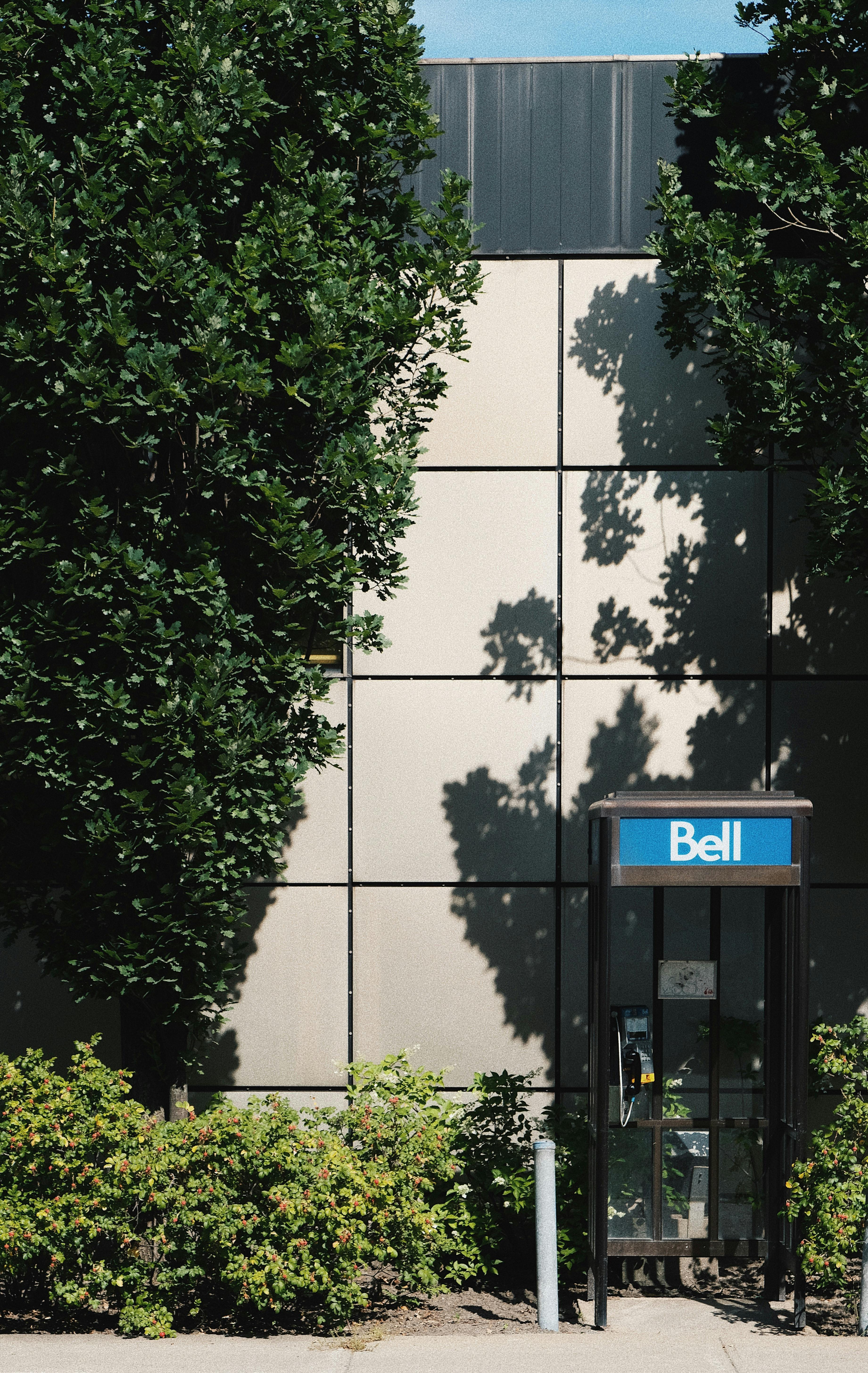 一张贝尔电话亭的照片，拍摄于一栋被树木和绿地环绕的建筑物外
