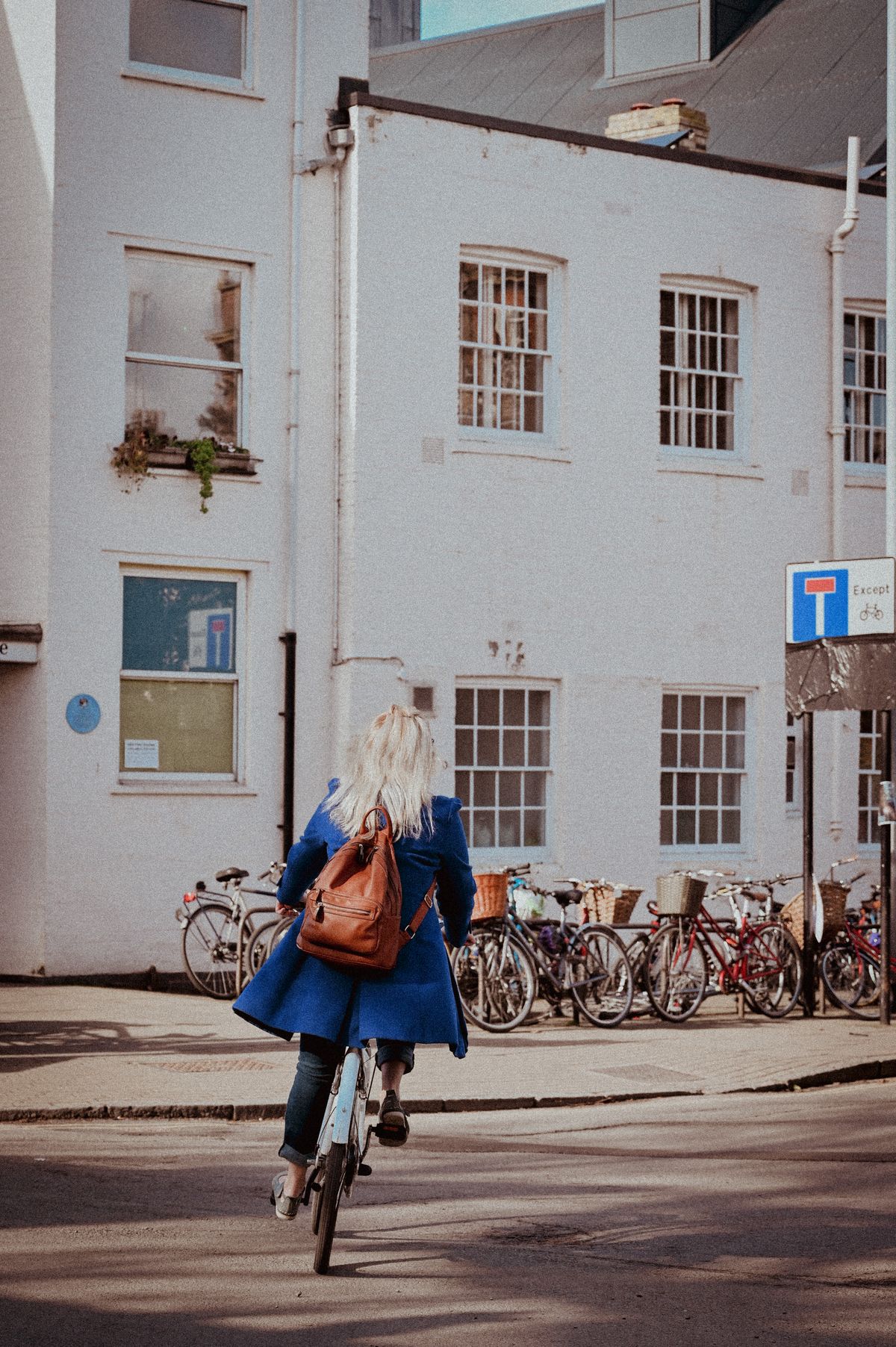 Woman riding a bicycle past parked bicycles on a modern city street