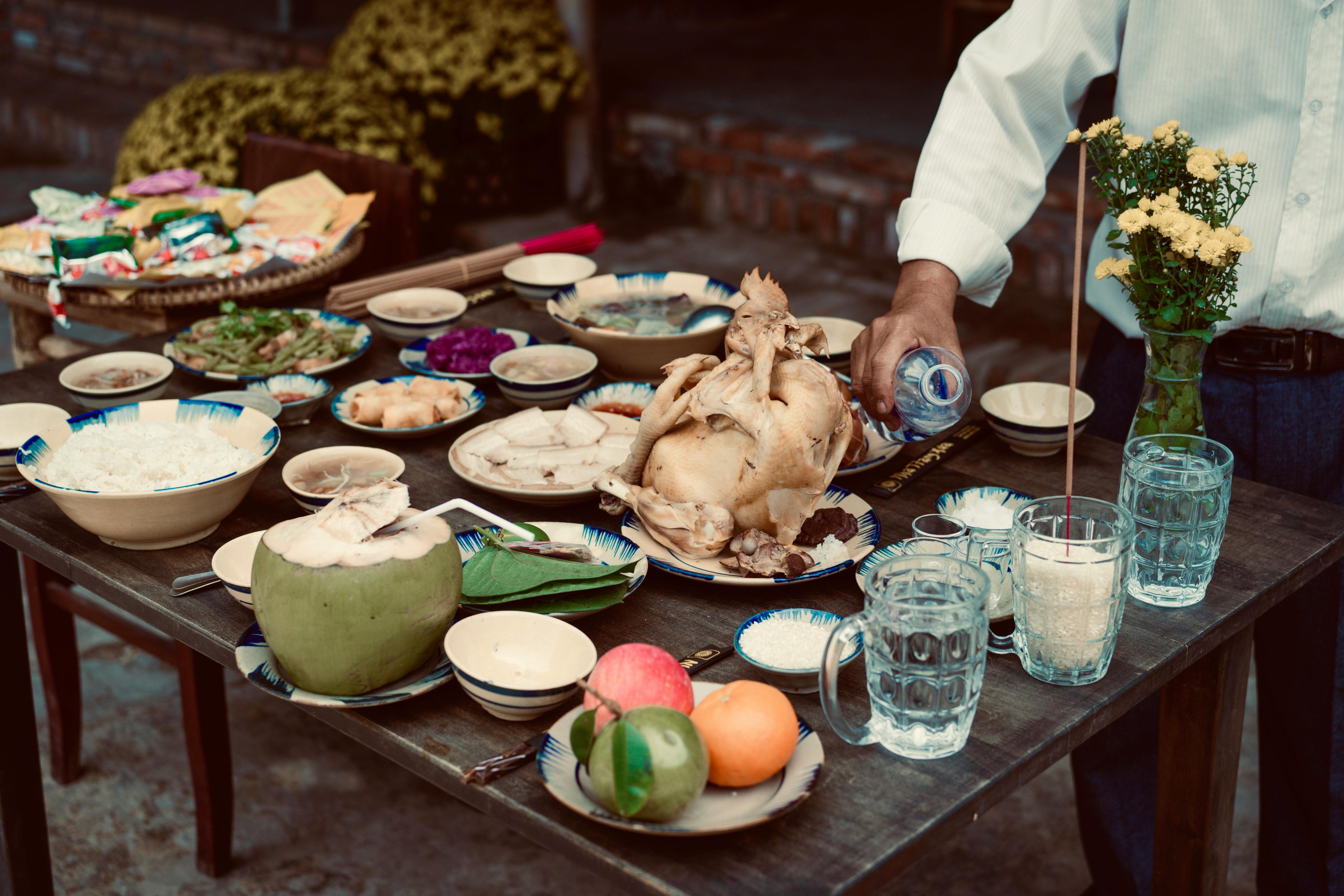A Vietnamese feast outdoors with chicken, rice, fruits, and drinks. Cultural dining experience.
