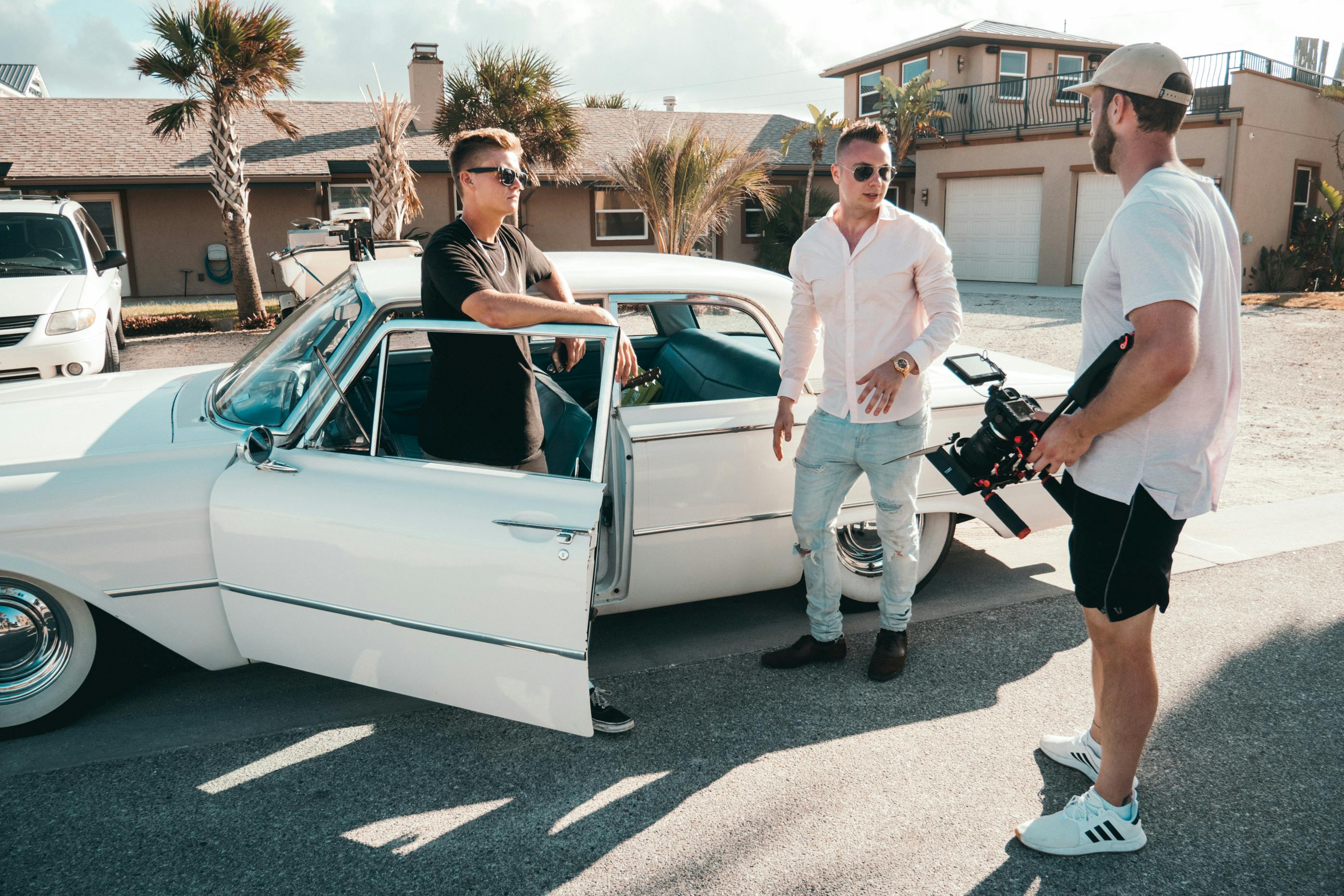 standing man wearing white dress shirt beside two men and white sedan