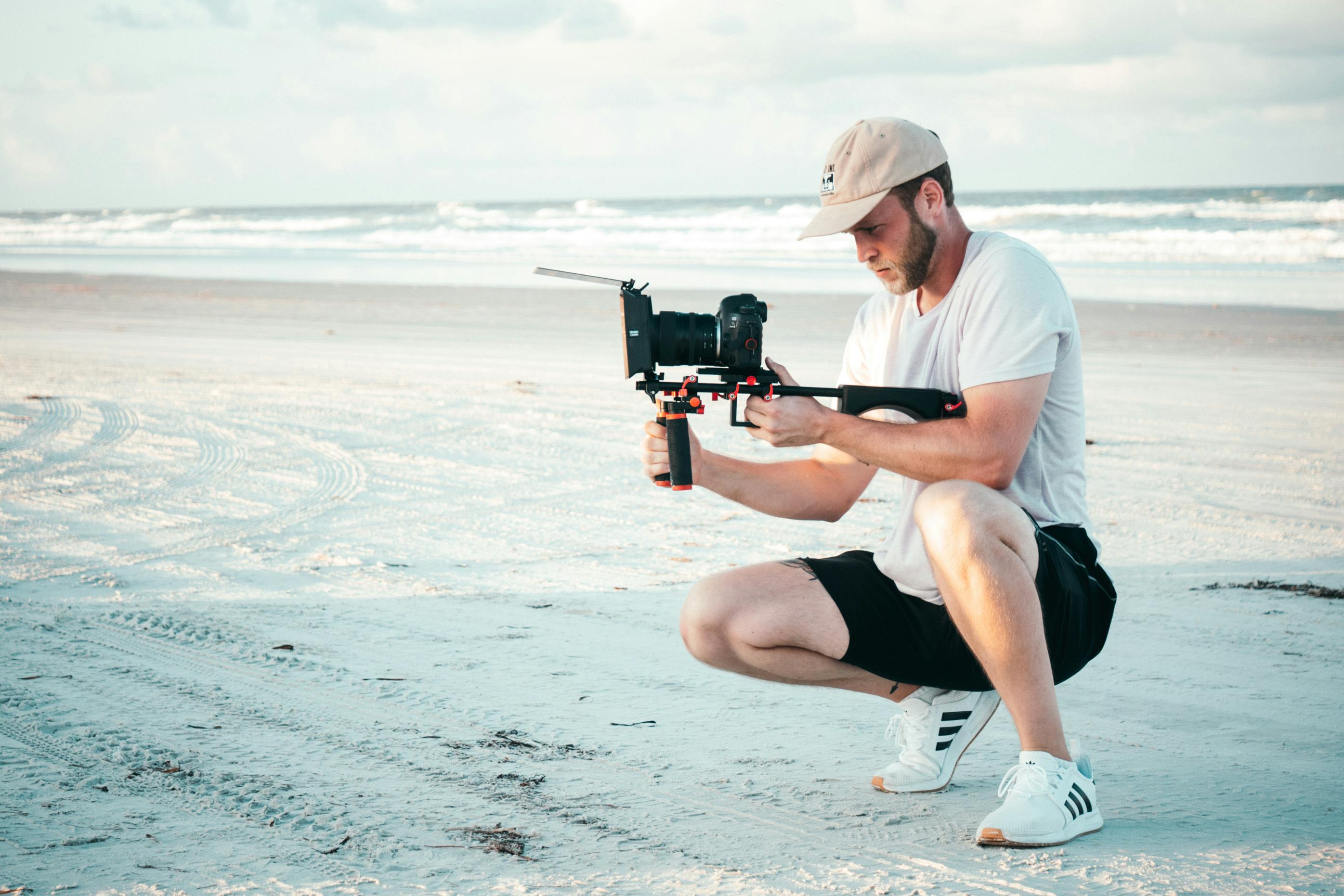 A person holding a video camera on a beach