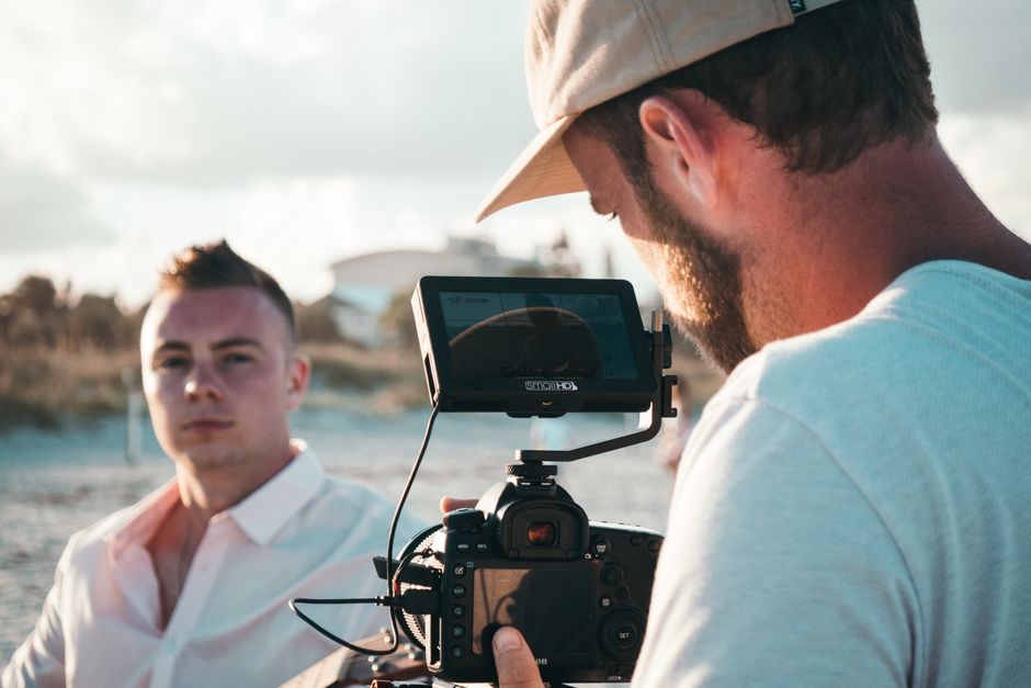Filmmaker captures a scene outdoors with professional video camera equipment and crew.