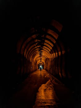 A silhouette of a person walking in a dramatically illuminated tunnel creating a moody ambience.