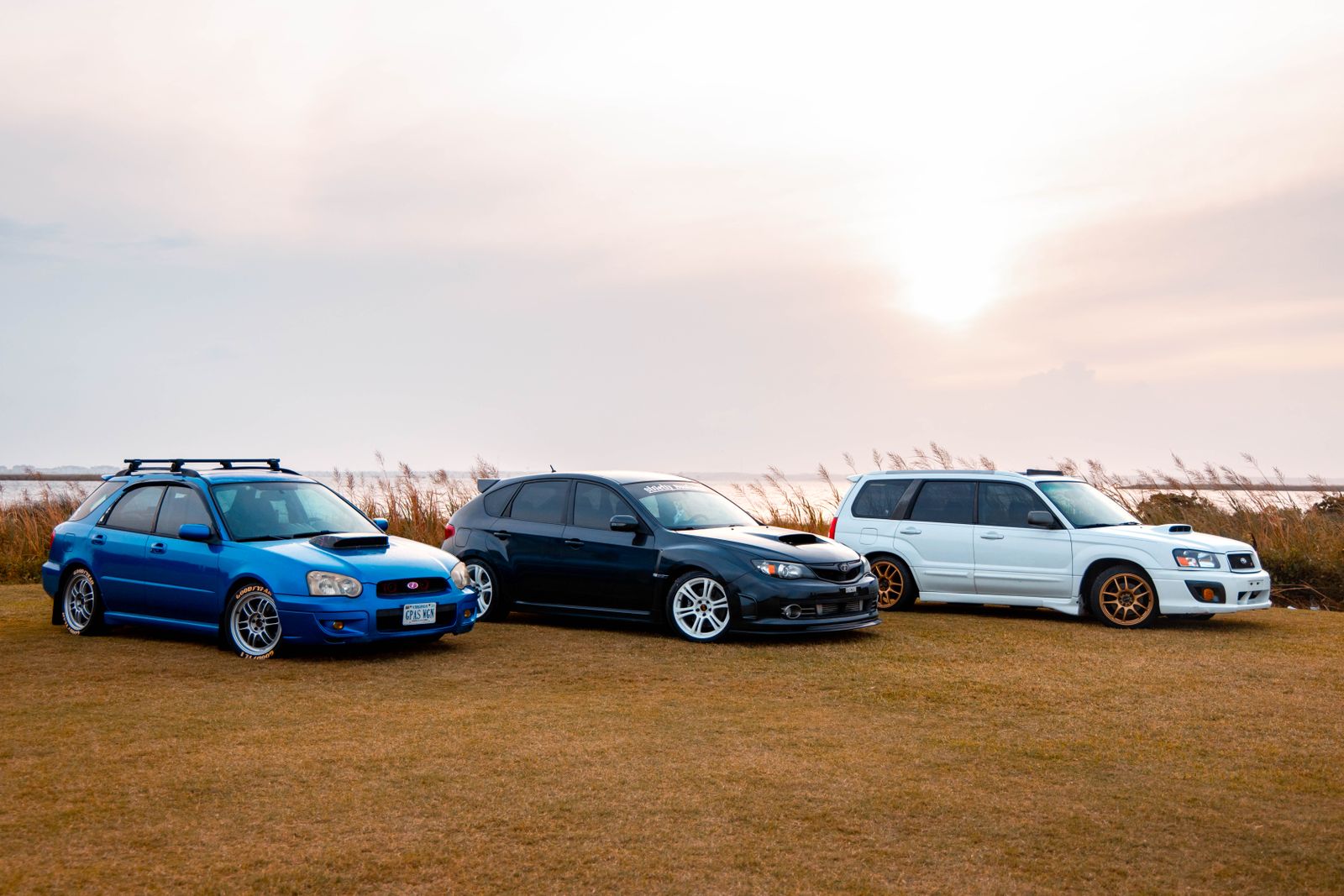 Three Subaru cars displayed outdoors at sunset, capturing the beauty and power of automotive design.