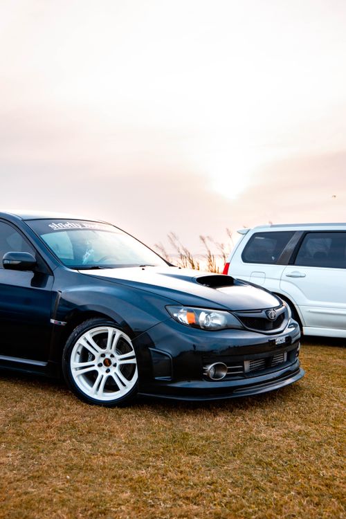 Free Black sports car with white rims parked outdoors at sunset, a stylish automobile scene. Stock Photo