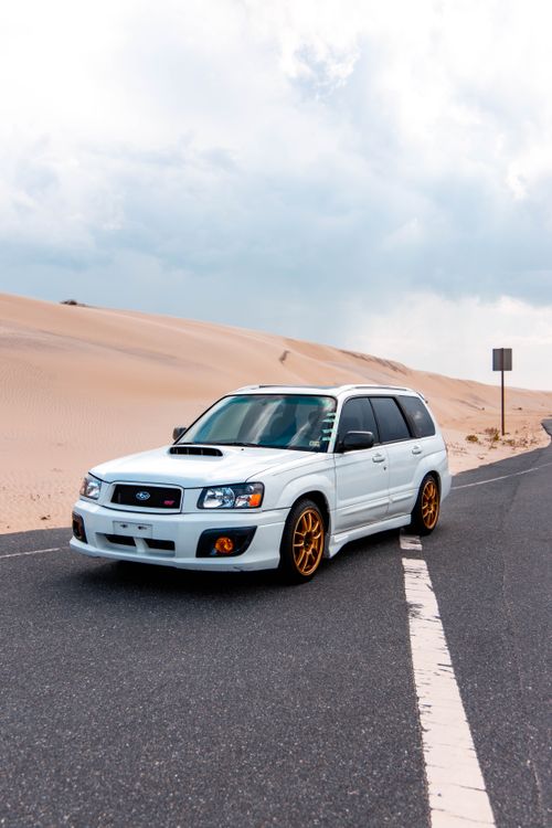 Free White SUV on a desert highway under cloudy sky. Perfect road trip setting. Stock Photo