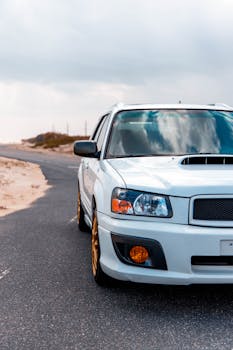 A white SUV parked on a winding desert highway under a blue sky.