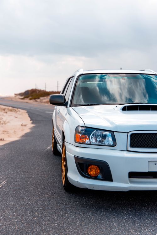 Free A white SUV parked on a winding desert highway under a blue sky. Stock Photo