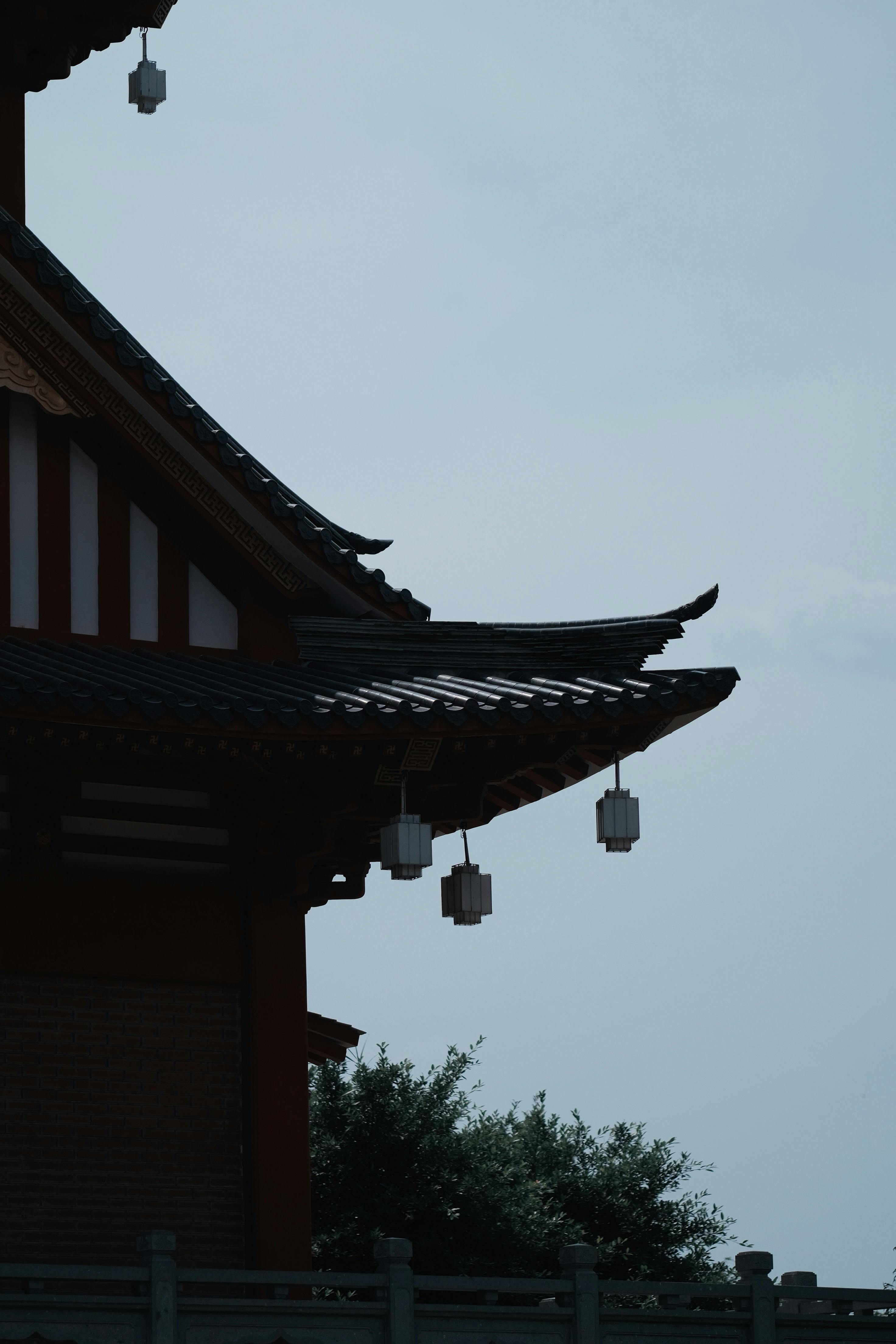 Gratuit Silhouette du toit d'un temple japonais traditionnel avec des lanternes suspendues contre le ciel. Photos