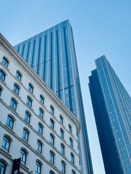 Perspective of modern skyscrapers reaching into a clear blue sky in Tianjin, China.