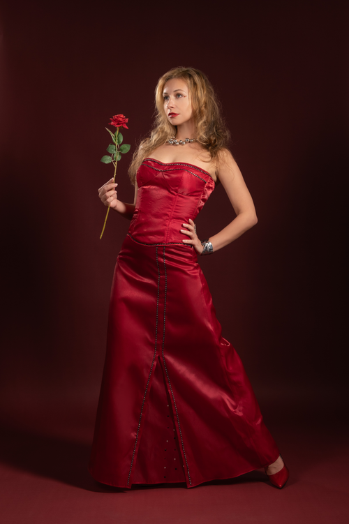 Free Woman in a stunning red gown holding a rose, stylish and graceful. Stock Photo