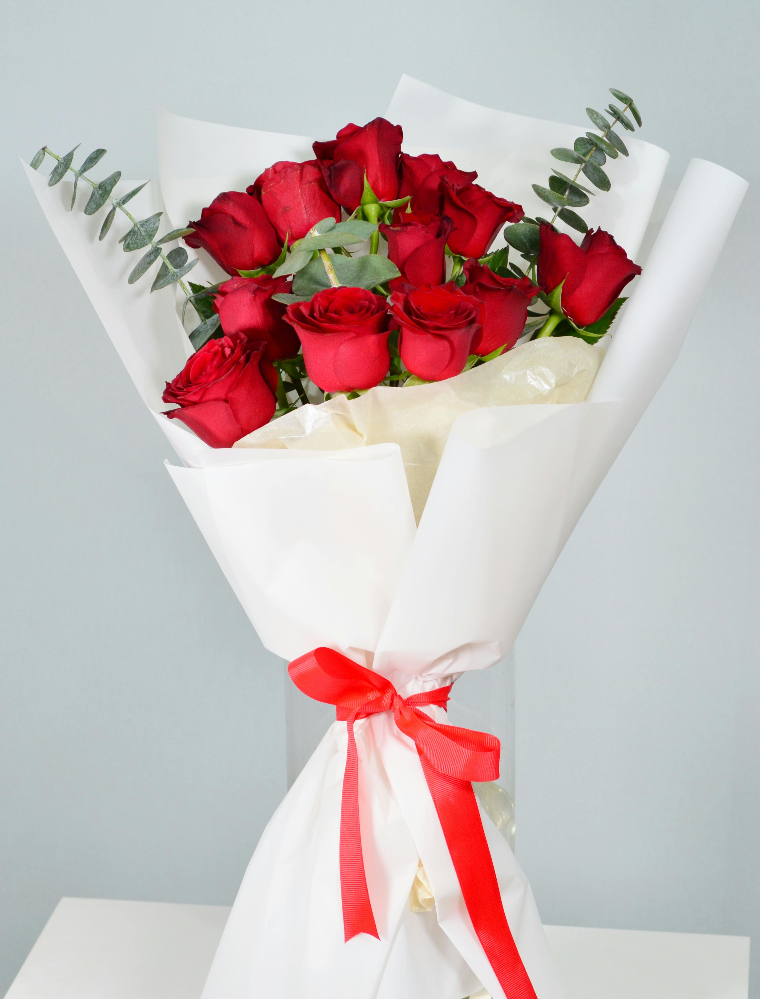 A beautiful bouquet of red roses wrapped with a red ribbon, perfect for special occasions.