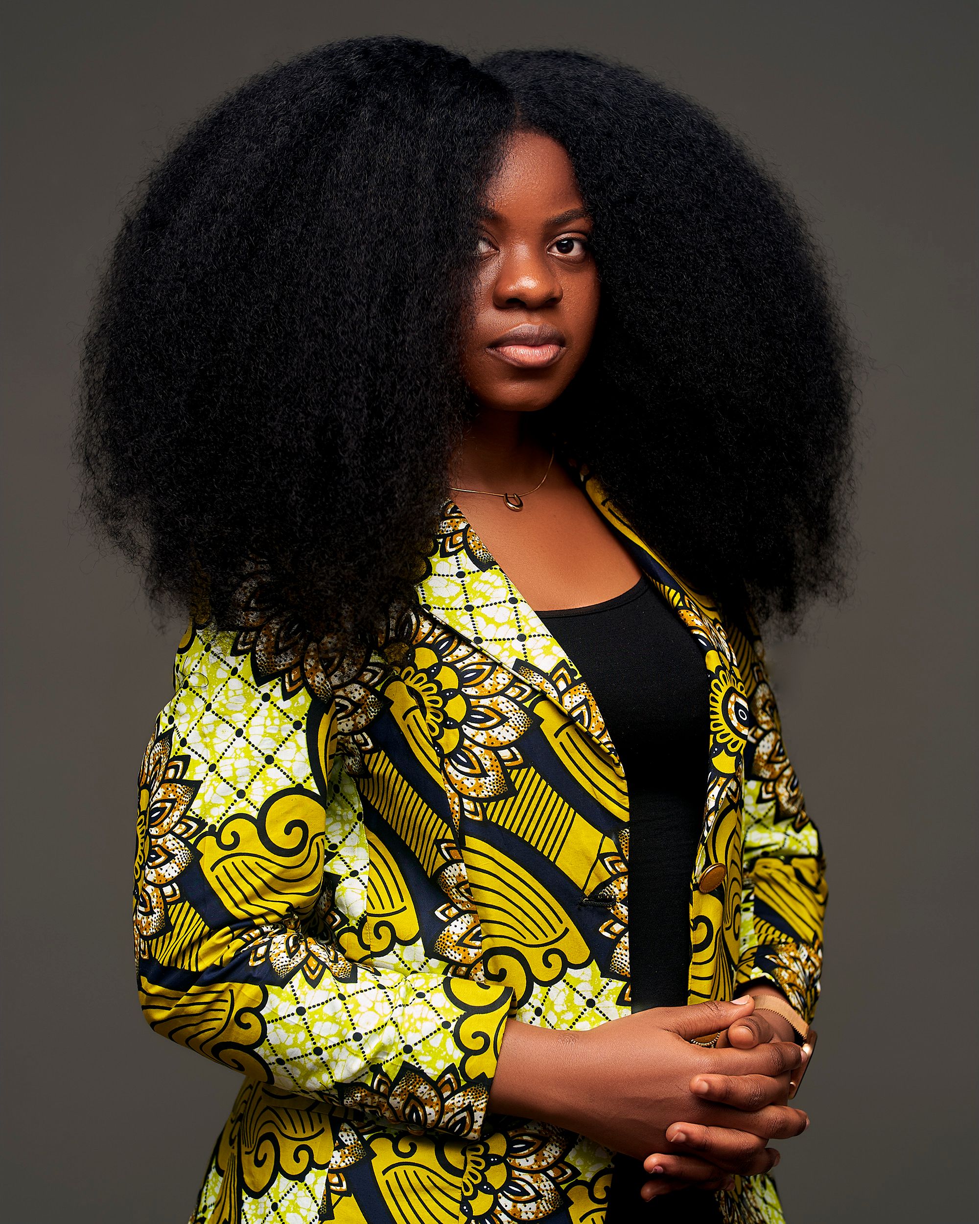 Elegant portrait of a woman with natural afro hairstyle in vibrant African print dress, Kinshasa.